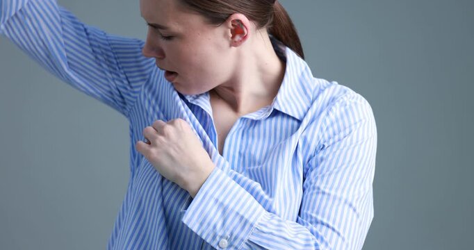 Woman suffering from sweating on grey background, closeup