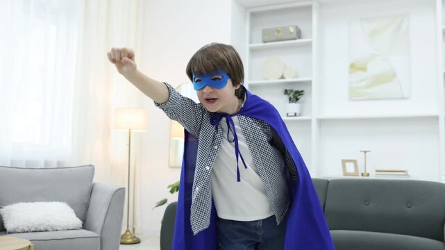 Little boy in superhero costume pretending to fly at home. Camera moving forward and backwards