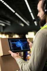 Male staff members monitoring AI-powered tracking tools on tablet, verifying parcel status with...