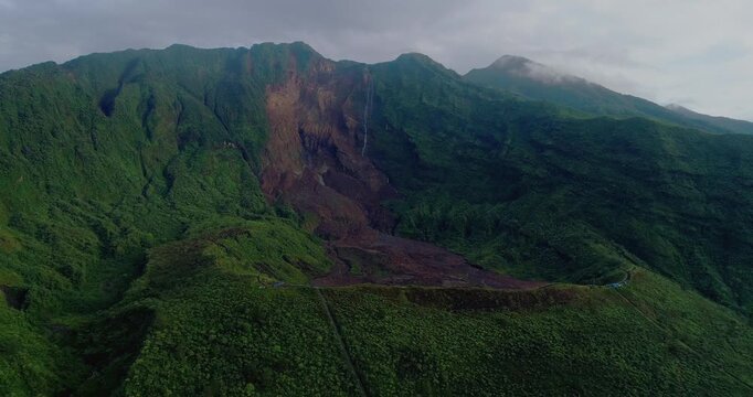 Drone view of tropical mountain valley with waterfall and drifting mist