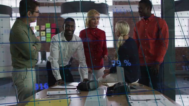 Blue overlay appearing on glass, team leaning at table, discussing biz metrics, smiling, posing