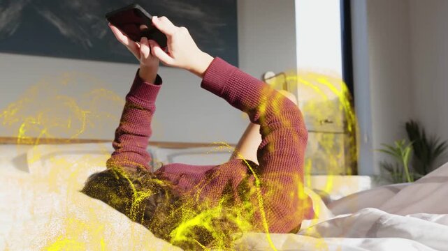 Lying woman tapping phone on bed tilting and causing gold particles swirling around body testing AR