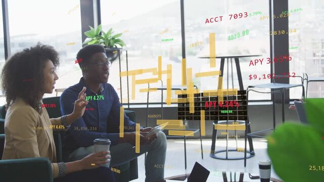 Seated woman pointing, man checking tablet as animated finance charts appearing, team discussing