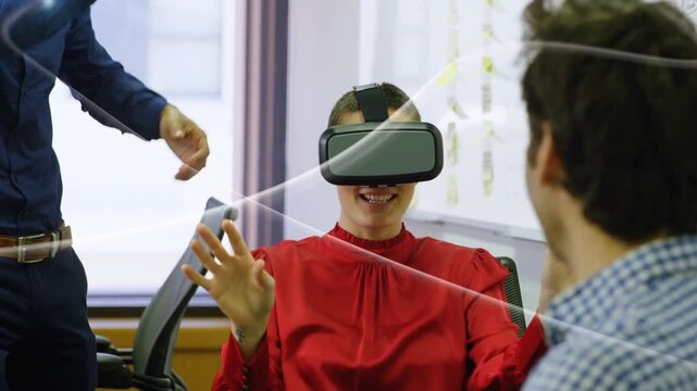 Woman wearing VR headset raising both hands and tapping floating UI while team guiding tech demo