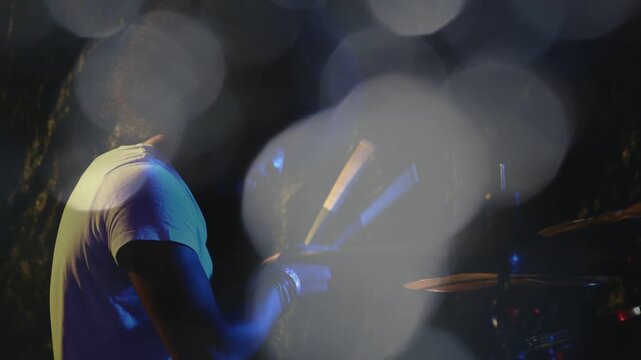 Male drummer starting strokes, striking cymbal and drum, bokeh revealing hands, keeping music beat