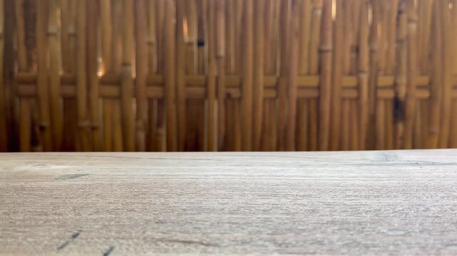 Empty wooden tabletop with bamboo fence background