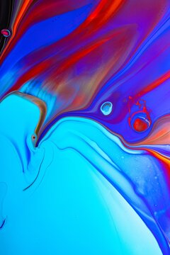 Fondo abstracto de arte fluido con remolinos de pintura acr&iacute;lica en azul vibrante, cian y rojo.