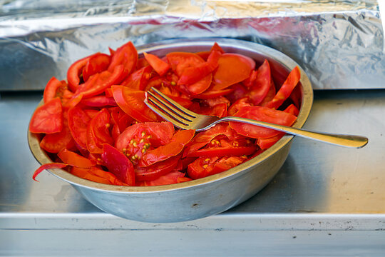 Fresh red tomato cut into pieces inside metal bowl on a market