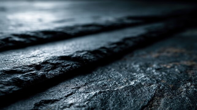 A dark, textured stone surface features prominent rough lines and grungy details, creating an abstract and moody background. The natural material exhibits a rugged pattern with varying shades of gray.