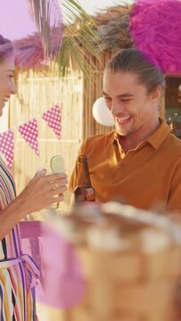 Vertical video: Man lifting beer flirting with woman at beach bar overlays obscuring duo for promo
