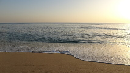 Fototapeta premium Gentle Waves Crashing on Shore During Early Morning. Beautiful cinematic shot of white sea foam washing over the sandy beach, capturing the tranquil atmosphere of the East Sea in South Korea.