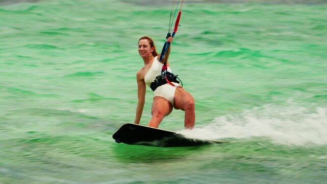 Sports woman kitesurfing in ocean in white bikini. Extreme summer sports