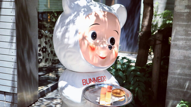 Bunmeido bear mascot statue holding a tray of honey castella cake and dorayaki pancake outside a traditional sweets shop in Nihonbashi district - Tokyo, Japan, June 14, 2024