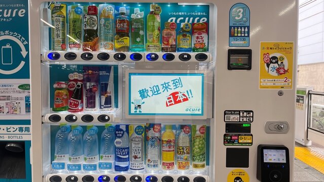 Modern Acure beverage vending machine at a JR East railway station platform featuring various bottled drinks and a digital screen welcoming visitors to Japan - Tokyo, Japan, August 28, 2023