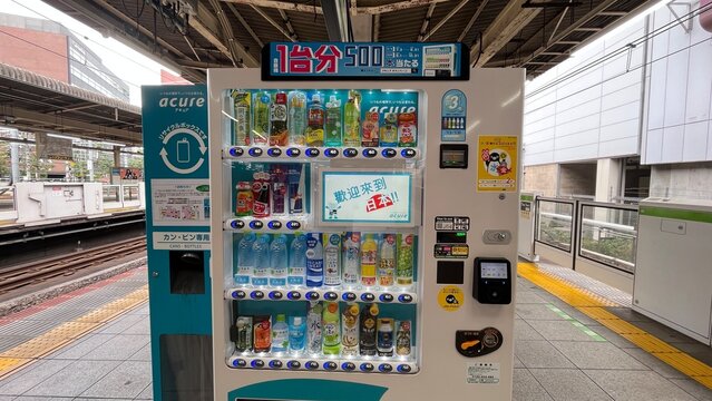 Acure vending machine on a JR East train platform with assorted beverages, recycling bin, and platform screen doors at Akihabara Station - Tokyo, Japan, September 12, 2024