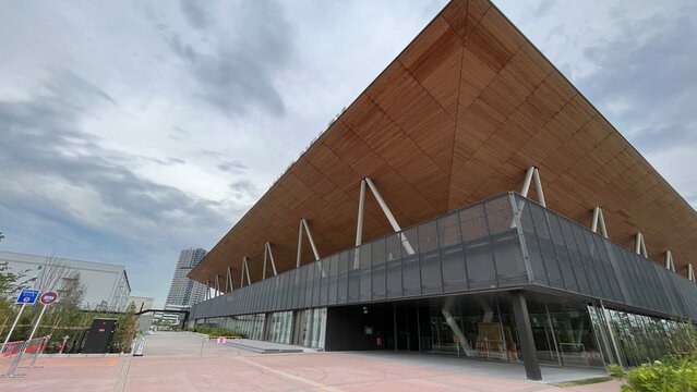 Ariake Arena modern architecture featuring large cantilevered wooden ceiling and glass facade under a cloudy sky in the Olympic district - Tokyo, Japan, October 15, 2024