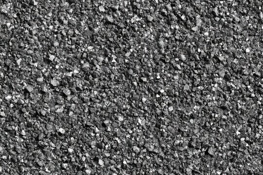 Close-up of a dark, gritty asphalt surface with small stones and pebbles