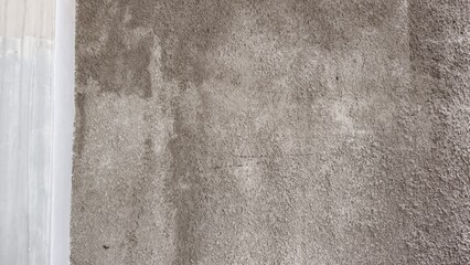 Fototapeta premium Rough grey concrete wall texture with a contrasting smooth white vertical edge.