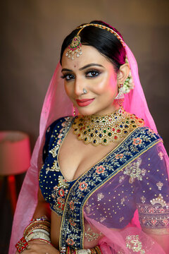 Stunning Indian bride wearing a traditional bridal lehenga with heavy gold jewellery, smiling gracefully in studio lighting