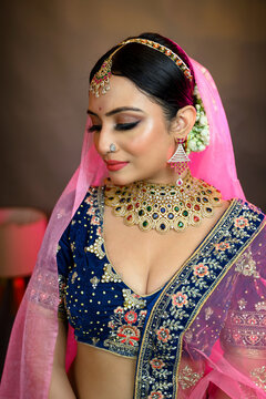 Stunning Indian bride wearing a traditional bridal lehenga with heavy gold jewellery, smiling gracefully in studio lighting