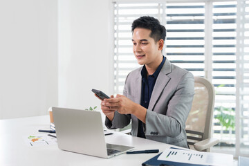 Fototapeta premium Business manager ceo using cell phone mobile app. Young businessman holding smartphone sitting in office working online on gadget.