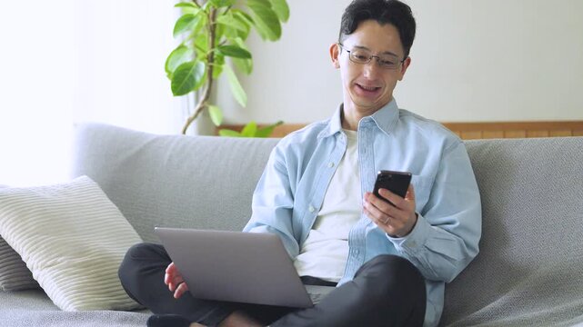 パソコンとスマートフォンを使う男性のライフスタイルイメージ, Man Using Laptop and Smartphone at Home Lifestyle Concept