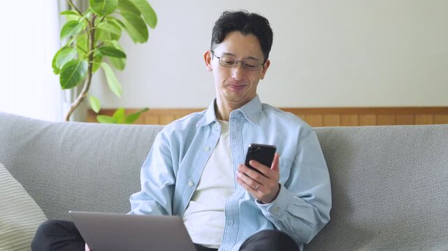 パソコンとスマートフォンを使う男性のライフスタイルイメージ, Man Using Laptop and Smartphone at Home Lifestyle Concept