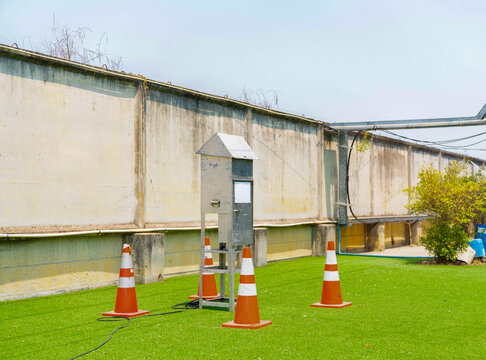 An outdoor environmental air quality monitoring station and sampling device installed on a lawn, secured with orange safety cones for industrial data collection.