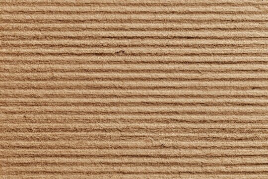 Close-up texture of parallel, embossed lines on a light brown surface