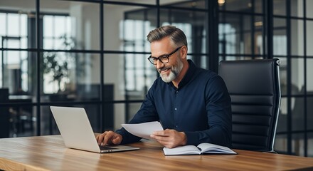 Fototapeta premium Businessman working on laptop at office desk with papers