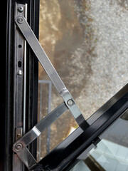Obraz premium Detailed close-up of a metal window hinge mechanism showing joints, screws, and frame structure.
