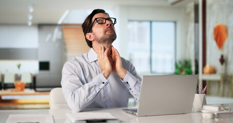 Obraz premium Man With Sore Throat Sits At Laptop Seeking Remote Care