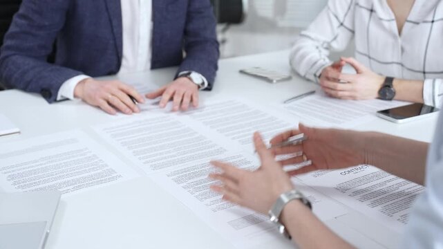 Business people discussing contract terms, outlining agreements, and reviewing legal documents during a corporate meeting, preparing for a significant partnership signing and negotiation