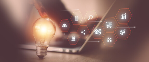 Businessman's hand is choosing light bulb with business creativity icons for plan to goal or creative idea innovation or analyzing marketing data management and target growth or human resources. © Eakrin