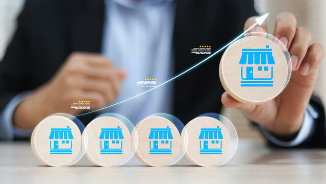 Businessman's hand chooses wooden toy stack with franchise icon for goal to growth is investment planning financial and branch expansion and management bank loans for marketing franchising.