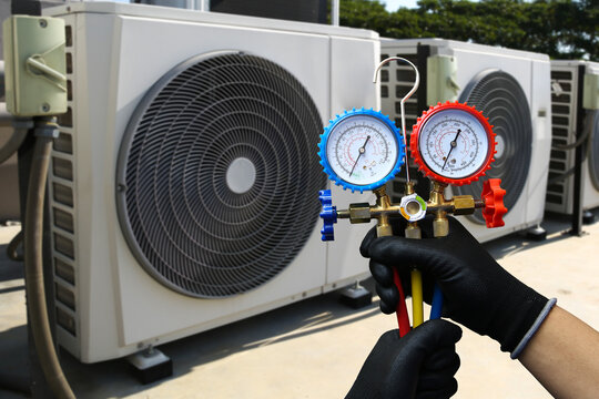 Air conditioning electrical technician service using measuring manifold gauge checking HVAC condition system and refrigerant filling air conditioner after cleaning and maintenance compressor units.