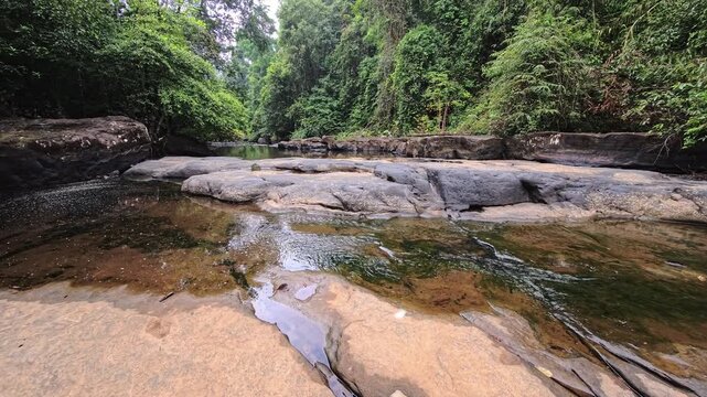Rocky tropical stream with shallow water over smooth stone slabs