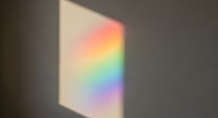 Naklejka premium A diagonal spectrum of rainbow light refracts across a plain gray wall, creating a prism effect with vibrant colors