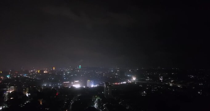 Night aerial view of a city skyline with a dramatic lightning strike illuminating the dark, stormy clouds above the urban lights.