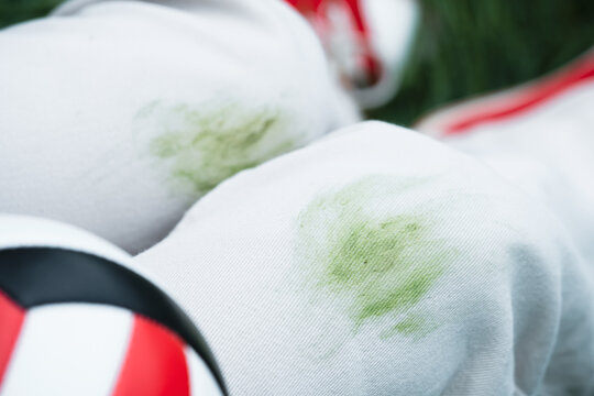 Close up of dirty stains on green grass during summer activities in the park outdoors. The individual is wearing red shoes and is outside near trees. Concept of daily stains on clothes. 