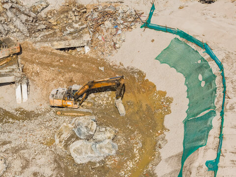 Large tracked excavator with hydraulic hammer breaks asphalt at a construction site