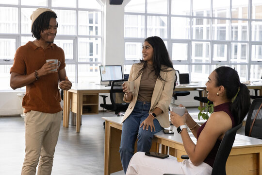 Three colleagues sharing coffee, man raising mug starting casual chat in flat animated office
