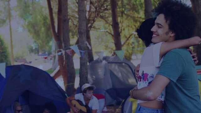 smiling hug starting, camping couple embracing, turning, animated flags highlighting guitar, tents
