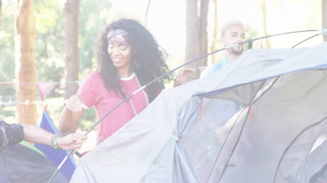 Left person bending and gripping pole base, campers guiding poles raising dome tent for camping