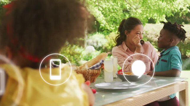 Mom feeding son and hugging at yard picnic, icons appearing obscuring then revealing them with tech