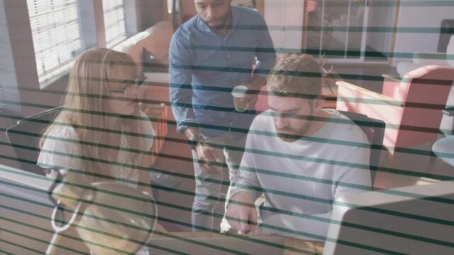 Three colleagues responding to standing colleague pointing, troubleshooting technology on monitor