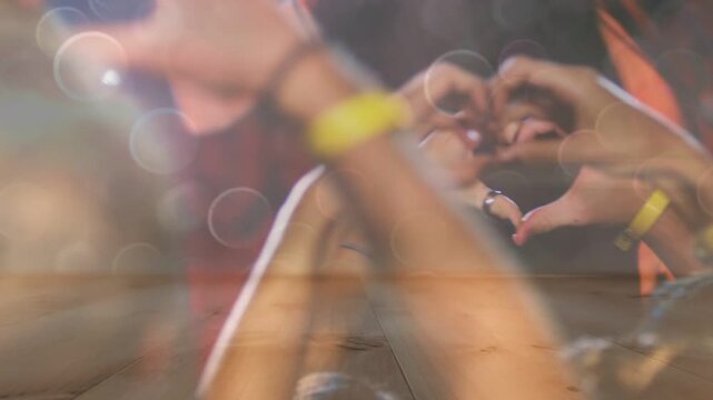 Music beat starting, crowd raising hands, forming heart shapes with wristbands, flares framing love
