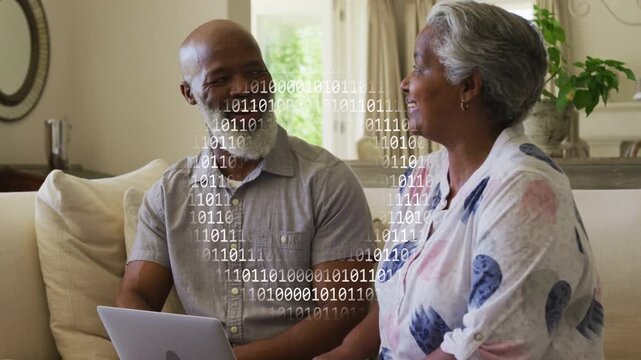 Pair sitting on light sofa talking while man scrolling laptop causing binary overlay for tech demo