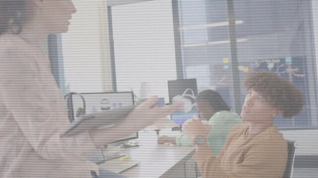 Standing woman approaching seated man in business, gesturing tablet chart and causing data review