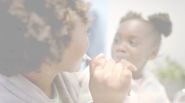 Mother starting brushing with brush at sink, guiding daughter into imitating and practicing health